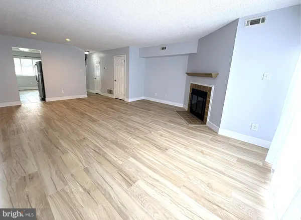 a view of empty room with wooden floor and fireplace