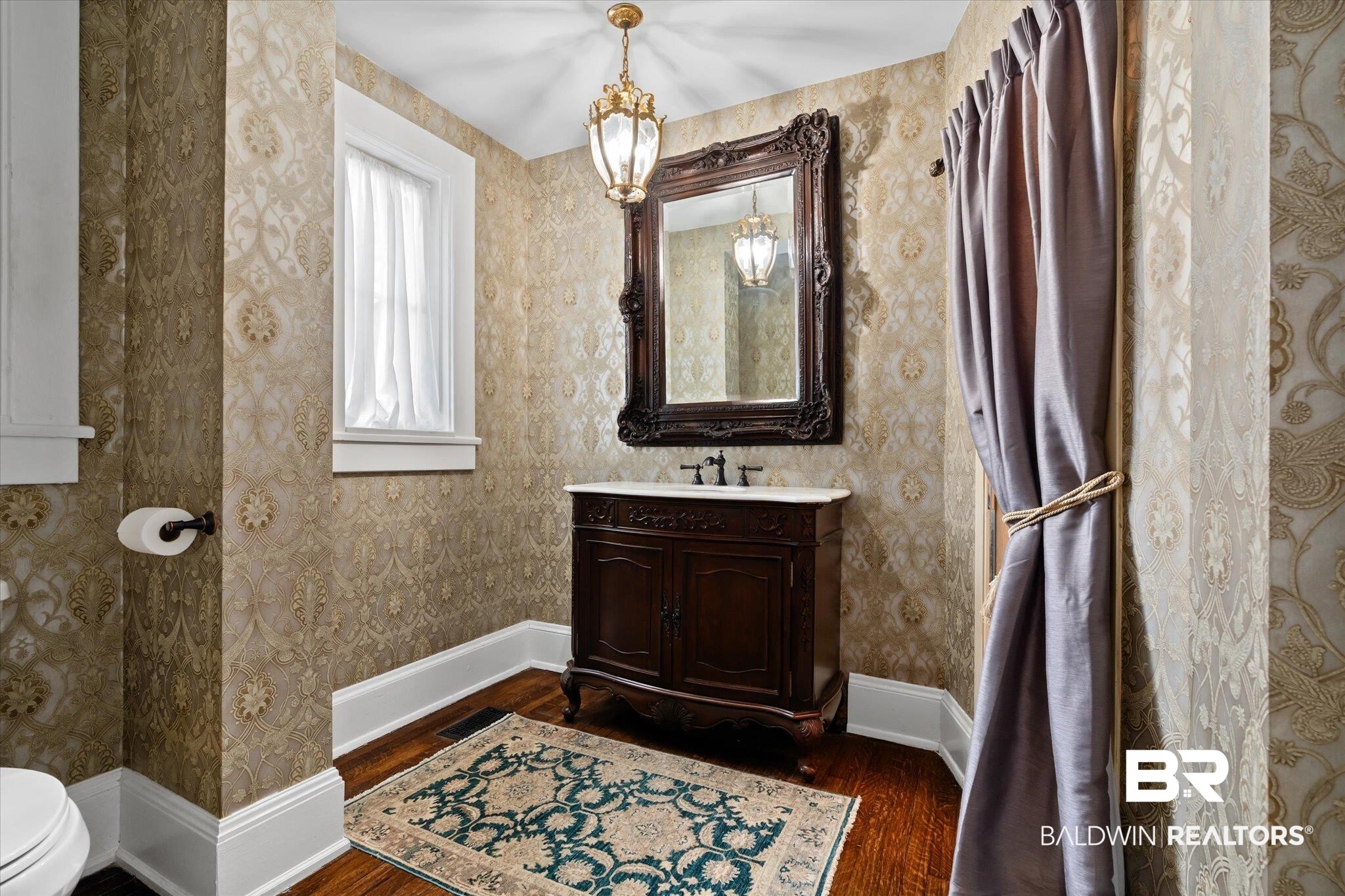 1953 Dauphin Street Mobile, AL 36606 - Photo 16 of 56 Bathroom featuring toilet, vanity, hardwood / wood-style flooring, and a notable chandelier