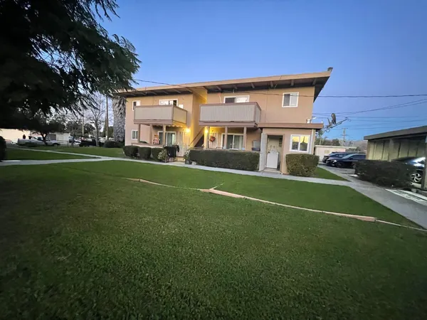 a view of house with a big yard and potted plants