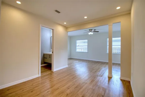 a view of an empty room with wooden floor and a window
