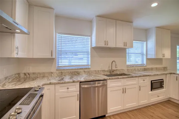 a kitchen with granite countertop stainless steel appliances white cabinets granite counter tops and a window