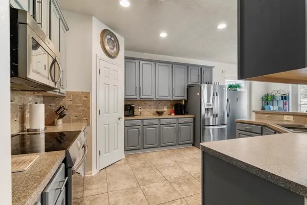 a kitchen with stainless steel appliances kitchen island granite countertop a refrigerator and cabinets