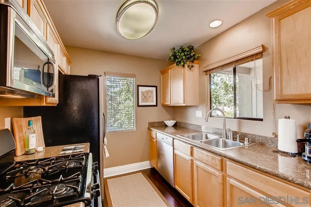 8213 Jade Coast Road, Unit 77 San Diego, CA 92126 - Photo 4 of 6 a kitchen with stainless steel appliances granite countertop a sink stove and refrigerator