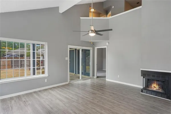 a view of an empty room with wooden floor fireplace and a window