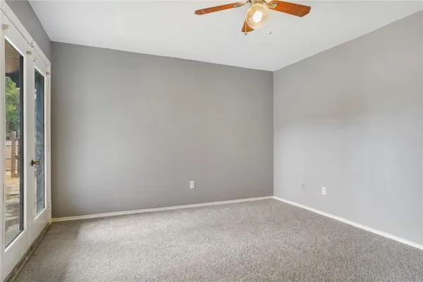 an empty room with a window and a ceiling fan