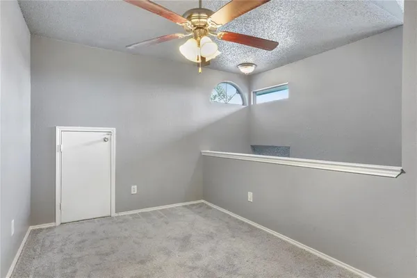 en empty room with chandelier fan and window