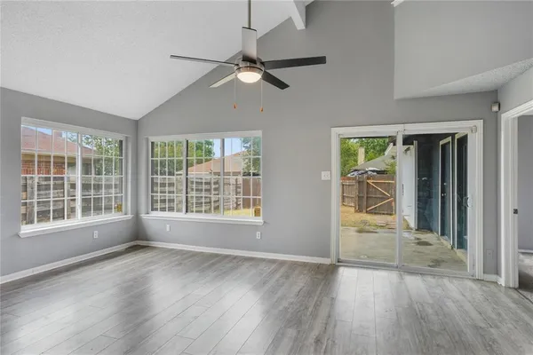 an empty room with wooden floor and windows