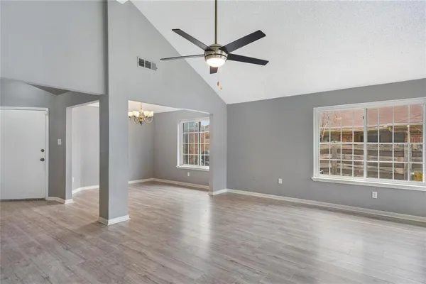 a view of an empty room with a window and wooden floor