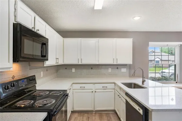a kitchen with a sink stove top oven and cabinets