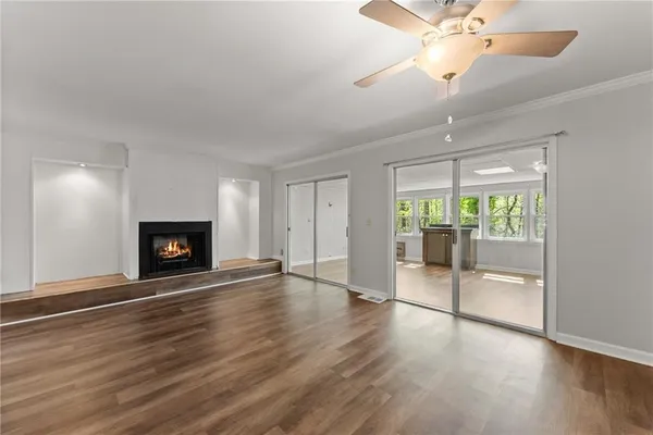an empty room with wooden floor fireplace and windows