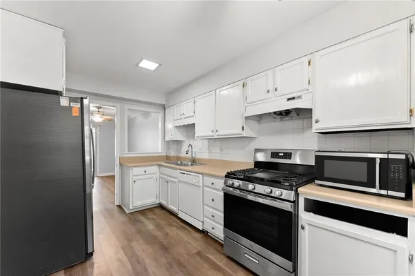 a kitchen with stainless steel appliances white cabinets and stove top oven