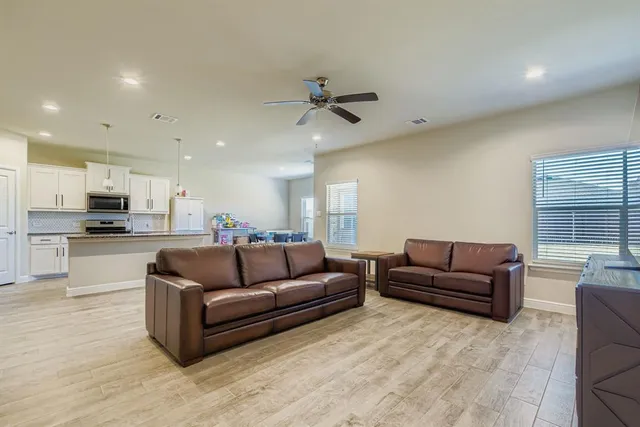 a living room with furniture kitchen view and a chandelier