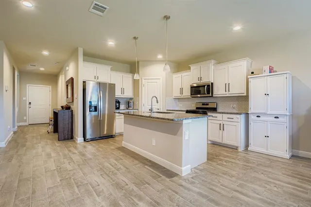 a large kitchen with stainless steel appliances a refrigerator and a stove top oven