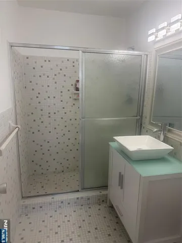 a bathroom with a granite countertop shower a sink and a mirror