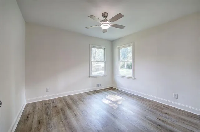 a view of an empty room with wooden floor and a window