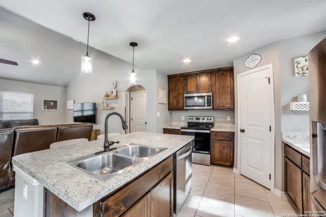a kitchen with granite countertop a sink a counter top space appliances and cabinets