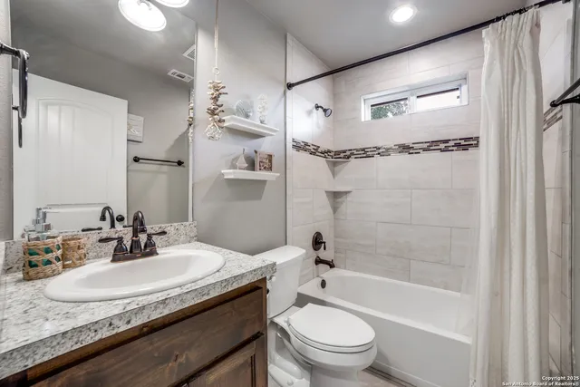 a bathroom with a granite countertop sink a toilet a mirror and shower