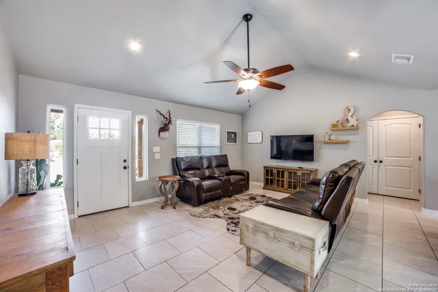 a living room with furniture a ceiling fan a rug and a window