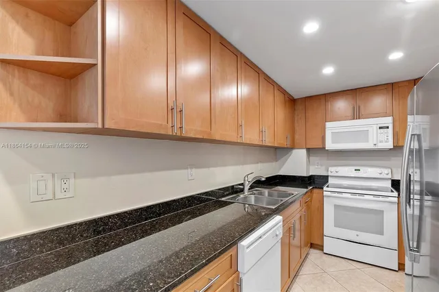 a kitchen with granite countertop a sink a stove and cabinets