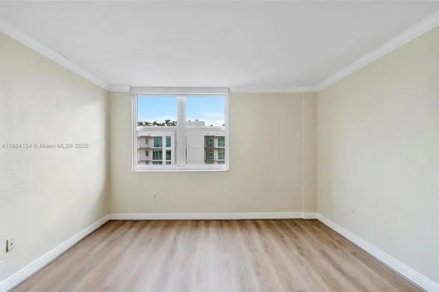 a view of an empty room with a window and wooden floor