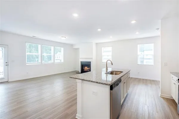 a kitchen that has a microwave a sink and a stove with wooden floor