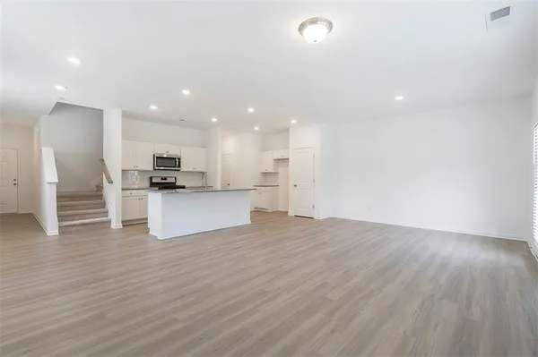 a view of kitchen with kitchen island wooden floor appliances and center island