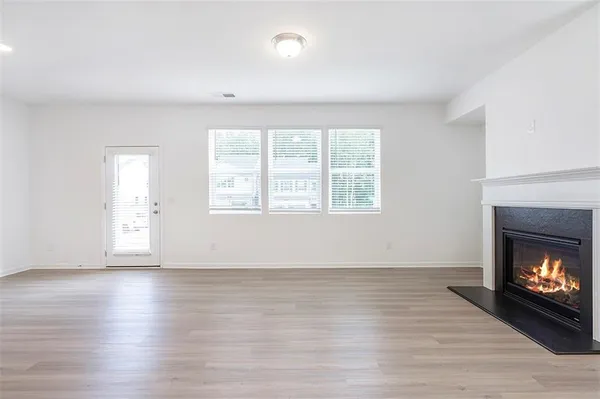 an empty room with wooden floor fireplace and windows