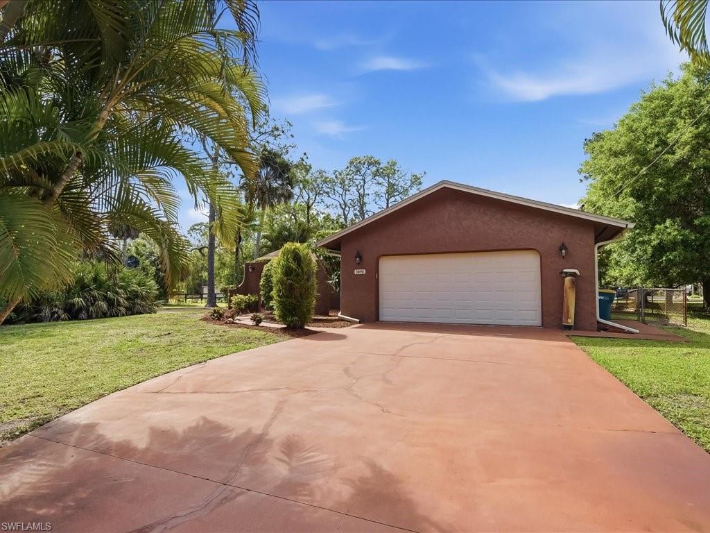 3890 27th Avenue Southwest Naples, FL 34117 - Photo 4 of 38 a front view of a house with a yard and garage