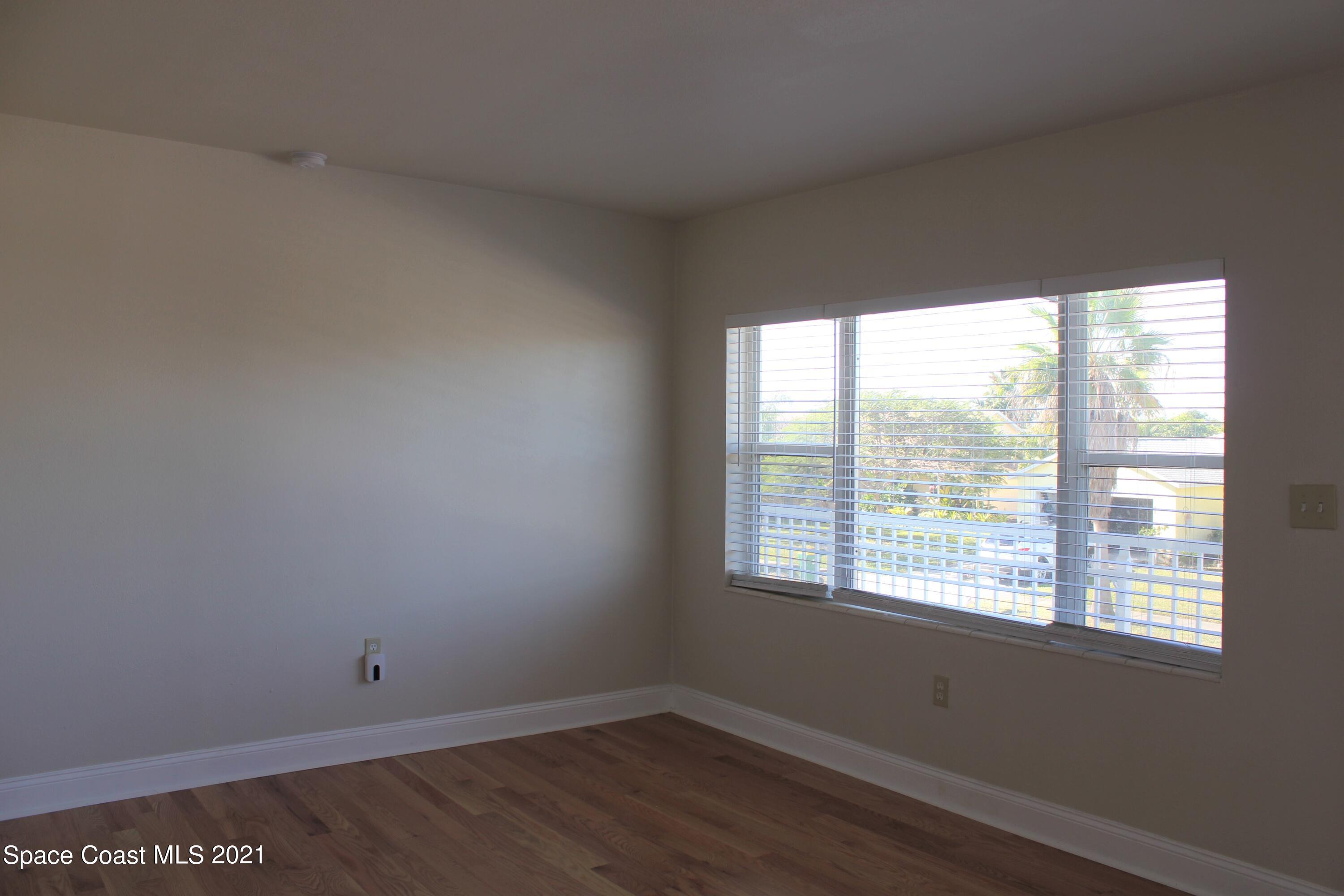 651 Palm Drive, Unit E3 Satellite Beach, FL 32937 - Photo 4 of 25 an empty room with wooden floor and windows