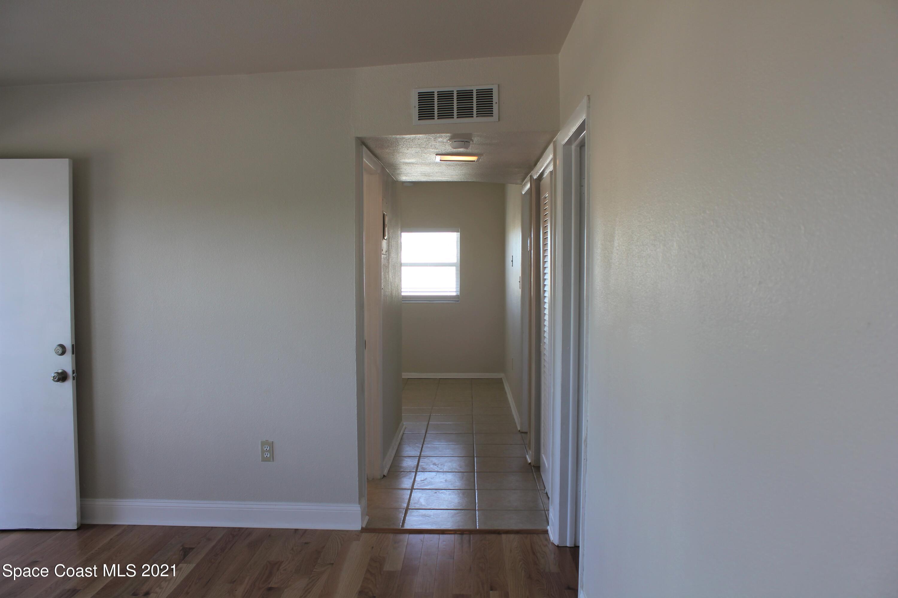 651 Palm Drive, Unit E3 Satellite Beach, FL 32937 - Photo 6 of 25 a view of a hallway with wooden floor and a living room