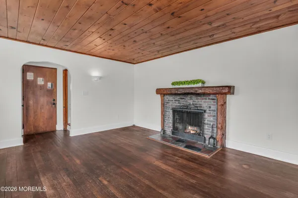 a view of an empty room with wooden floor and a fireplace