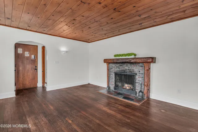 a view of an empty room with wooden floor and a fireplace