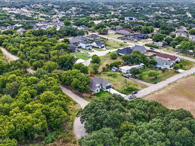 an aerial view of residential houses with outdoor space and trees