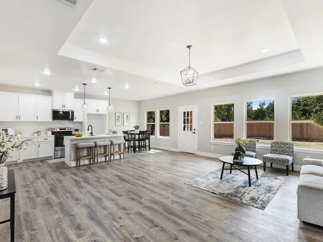 a living room with furniture and kitchen view with wooden floor