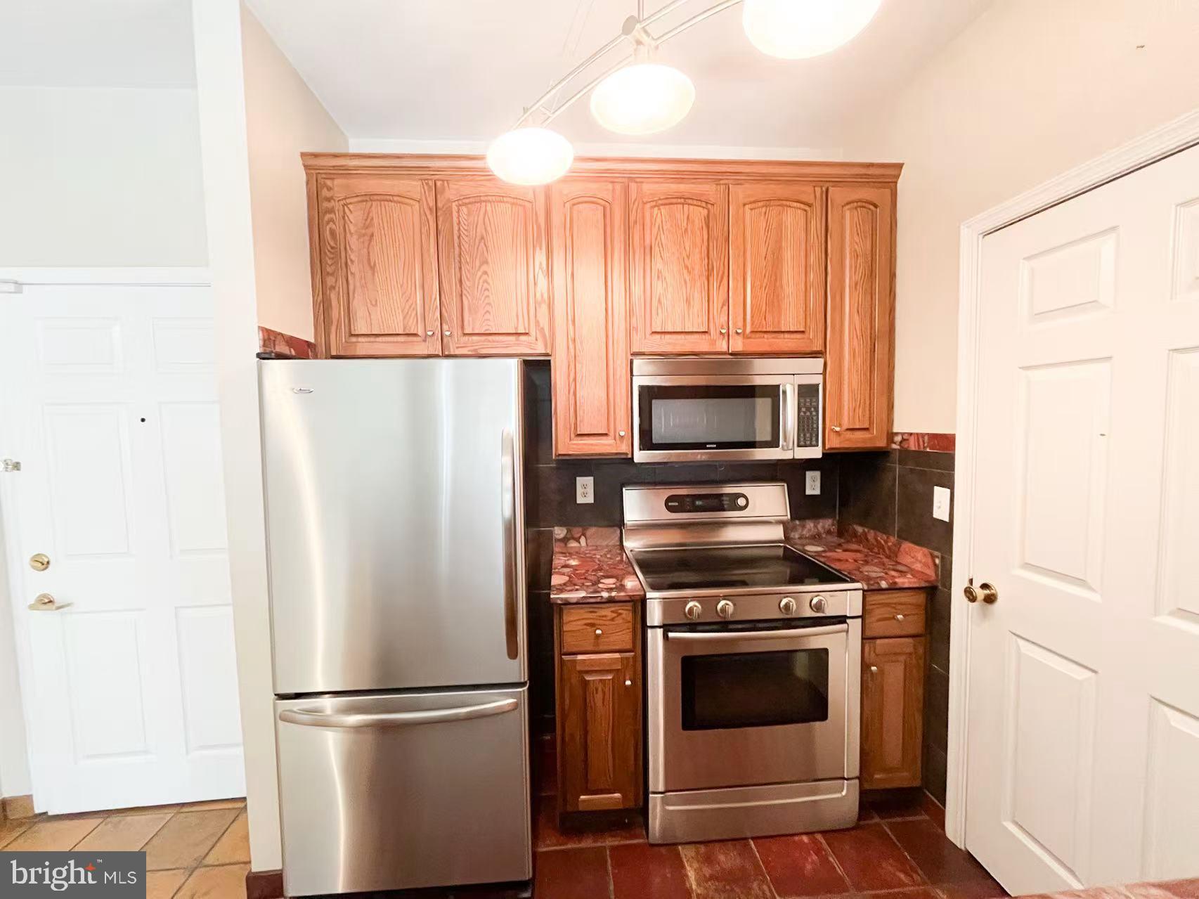 1570 Spring Gate Dr., Unit 7109 McLean, VA 22102 - Photo 5 of 21 a kitchen with granite countertop a refrigerator stove and microwave