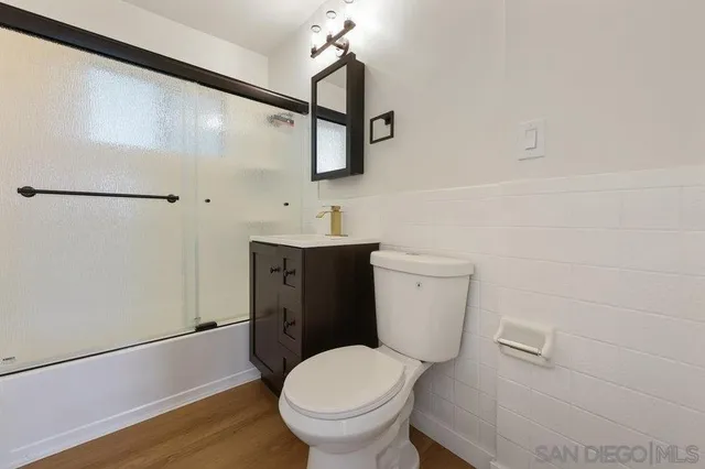 a bathroom with a toilet a sink and wooden floor