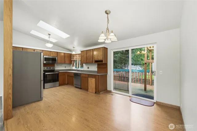 a view of a kitchen with stainless steel appliances granite countertop a refrigerator and a wooden floor