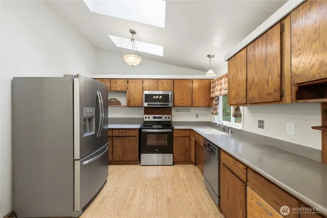 a kitchen with stainless steel appliances granite countertop a refrigerator oven a sink dishwasher and a stove