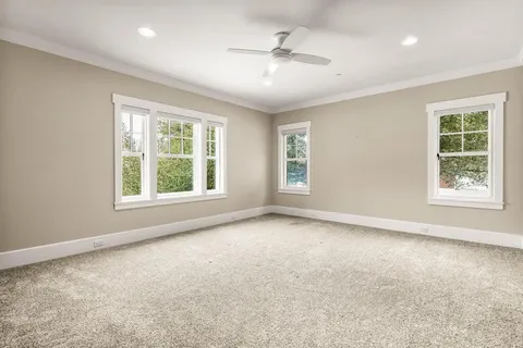 an empty room with windows and chandelier fan