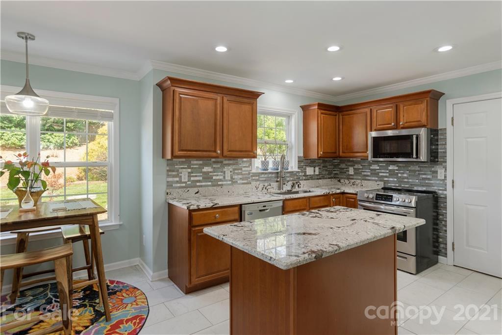 312 Black River Road Fletcher, NC 28732 - Photo 12 of 29 a kitchen with a stove a sink a microwave a dining table and chairs