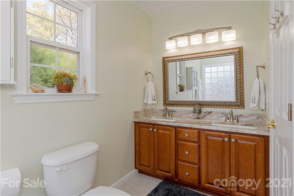312 Black River Road Fletcher, NC 28732 - Photo 18 of 29 a bathroom with a granite countertop toilet a sink a mirror and a window