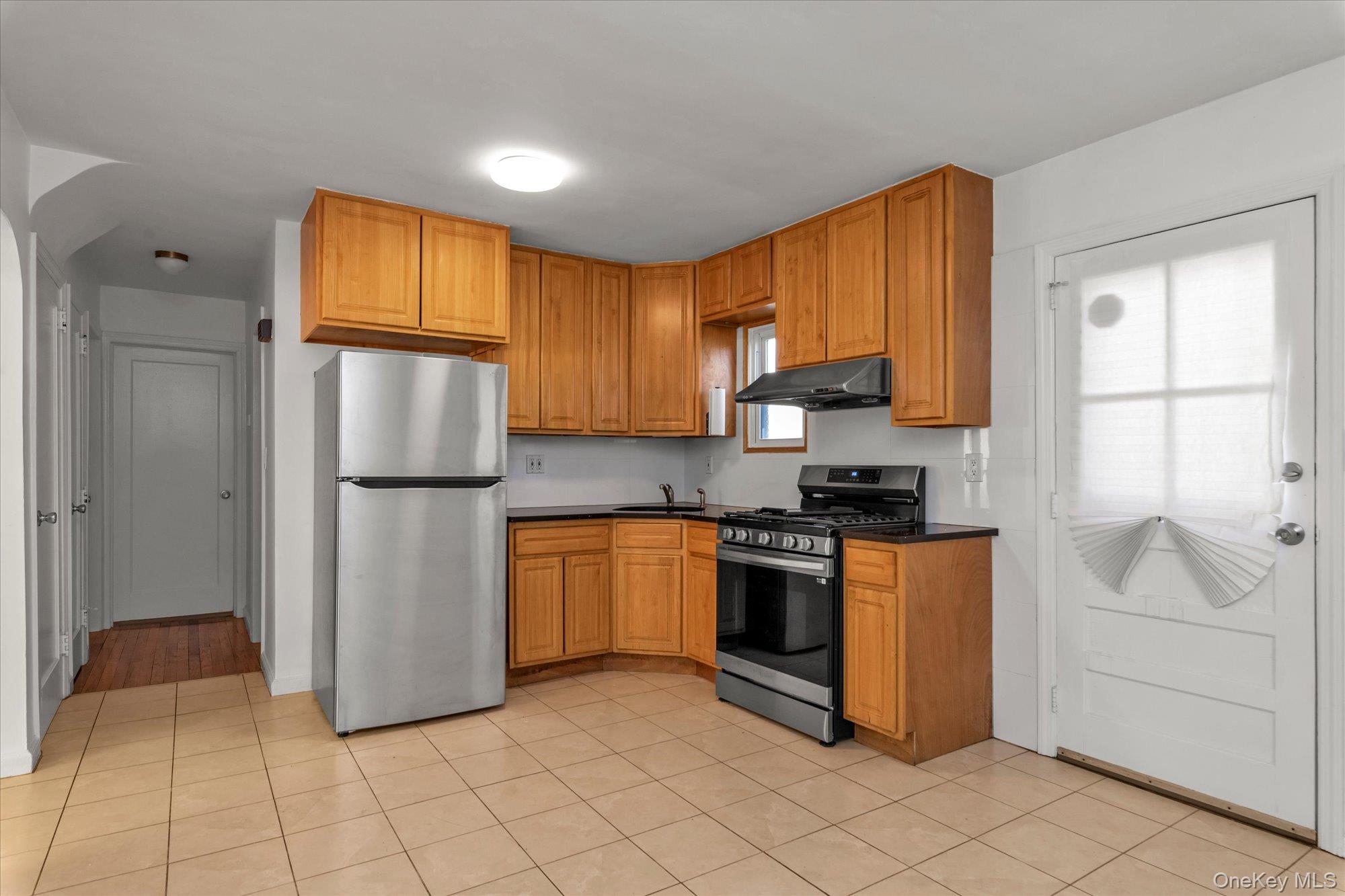 5 White Street Valley Stream, NY 11580 - Photo 6 of 23 a kitchen with white cabinets a refrigerator and a sink