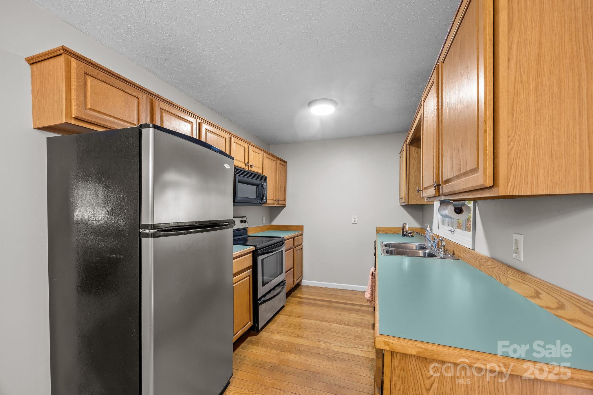 3228 Sweeten Creek Road Asheville, NC 28803 - Photo 30 of 48 a kitchen with stainless steel appliances granite countertop a refrigerator a stove and a sink with wooden floor