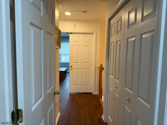 a view of a hallway with wooden floor and closet area