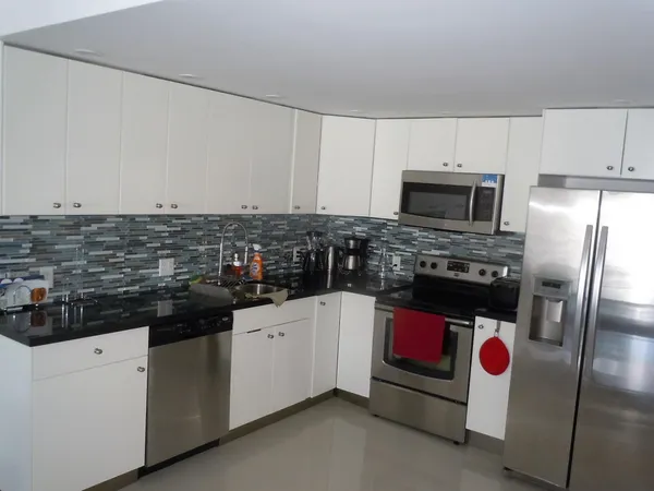 a kitchen with stainless steel appliances kitchen island granite countertop a stove a sink and white cabinets
