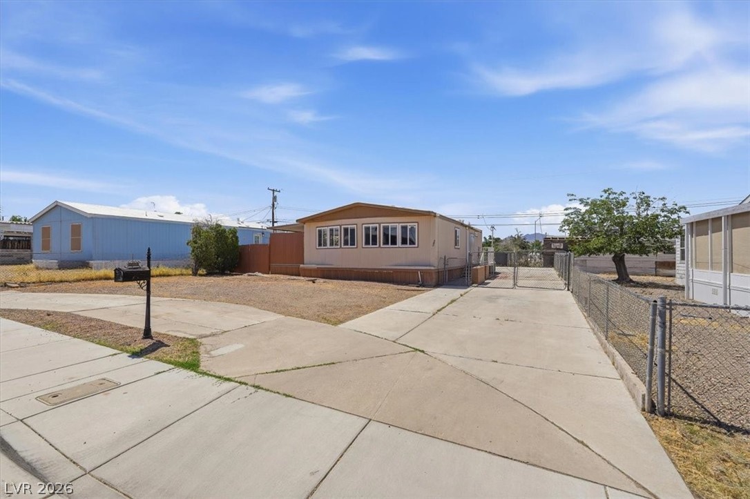 283 Aztec Lane Henderson, NV 89015 - Photo 2 of 21 A modest home presents a large concrete driveway and a secured, fenced yard.