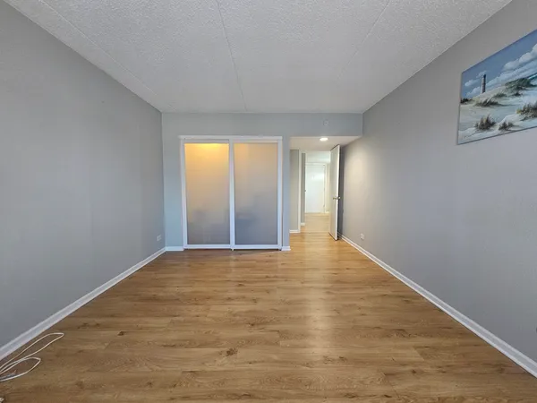 a view of an empty room with window and wooden floor