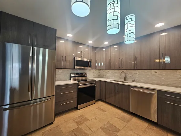 a kitchen with stainless steel appliances granite countertop a sink a stove a refrigerator and a refrigerator
