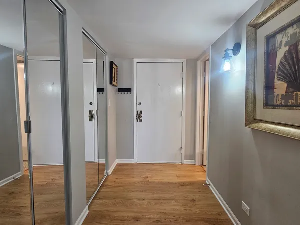 a view of a hallway with wooden floor and a bathroom