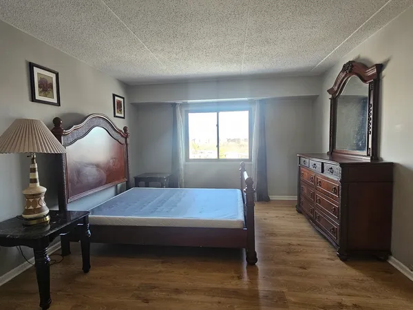 a bedroom with a bed wooden floor and window